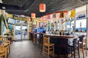 Eine Bar mit Holzhöckern und einer Theke, auf der verschiedene Flaschen stehen.
