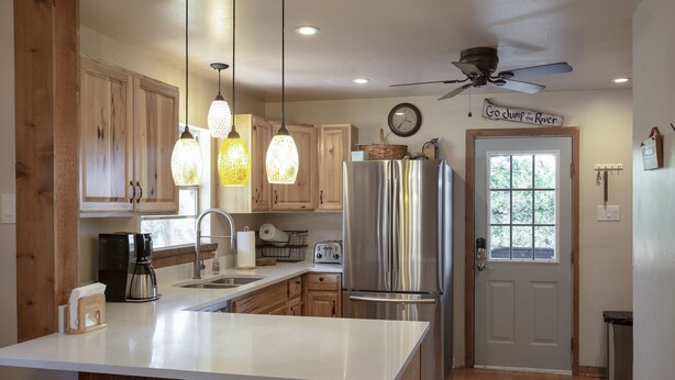 A kitchen with wooden cabinets, a stainless steel refrigerator, a coffee maker, and pendant lights.