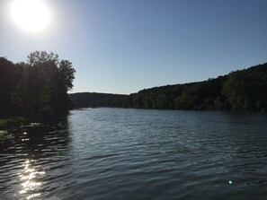 A river with a forested bank and a clear sky.