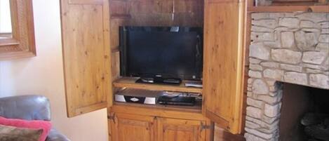 A wooden entertainment center with a television, DVD player, and gaming console.
