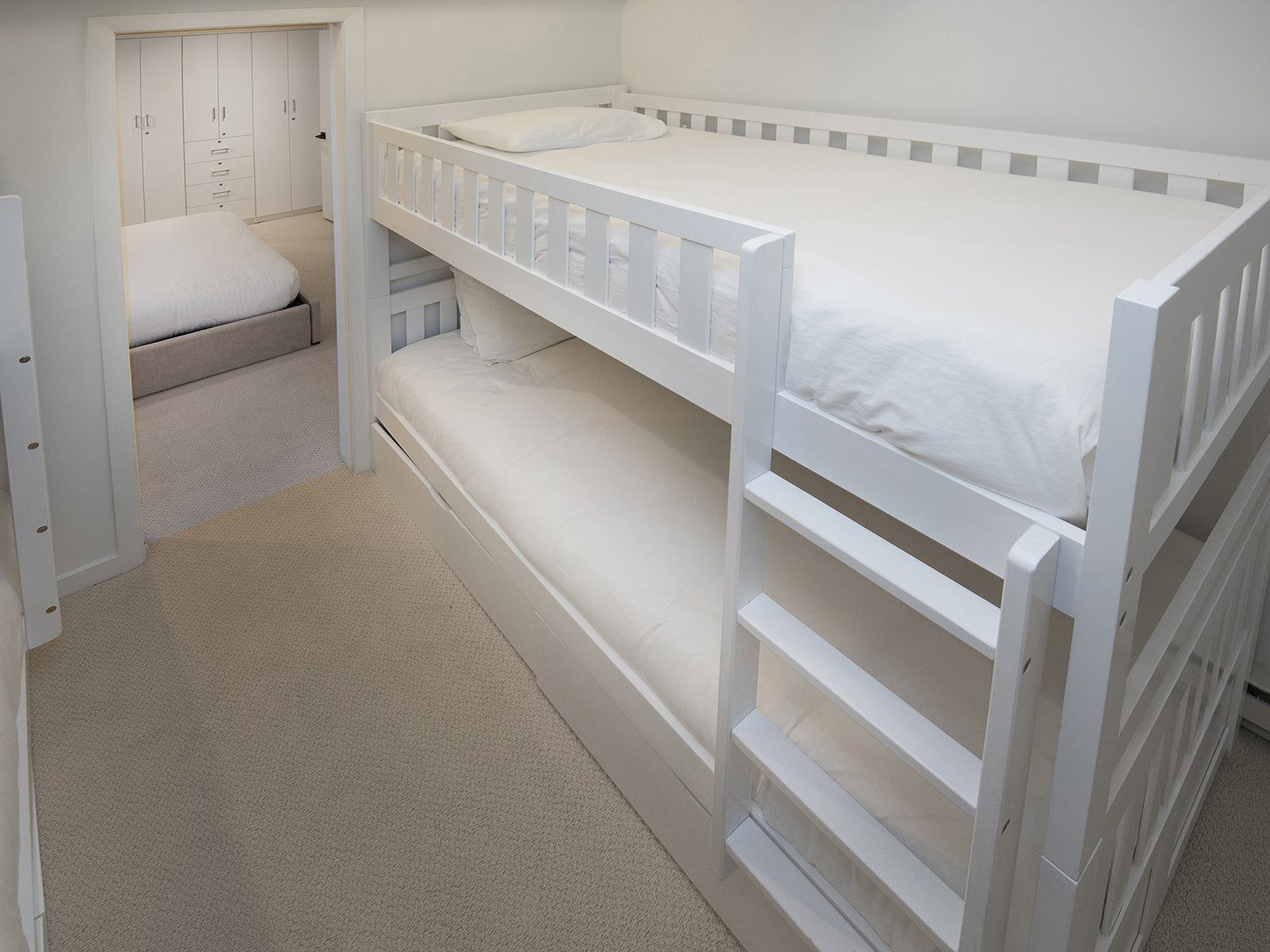 Ein Schlafraum mit Etagenbett, Kleiderschrank und einer kleinen Sitzecke.