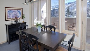 En matplats med ett träbord och stolar, en vas med vita blommor och ett inramat konstverk på väggen.