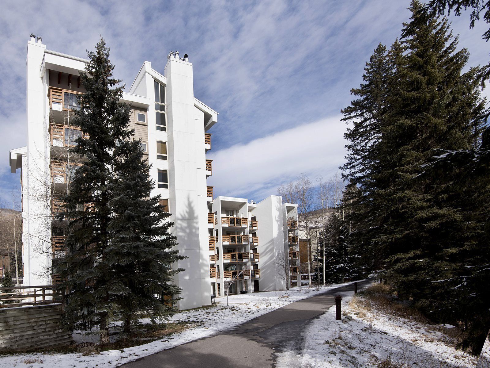 Un edificio de apartamentos moderno con varios balcones y un suelo cubierto de nieve.