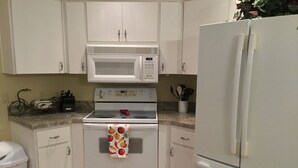 Una cucina con mobili, piano cottura e frigorifero tutti bianchi.
