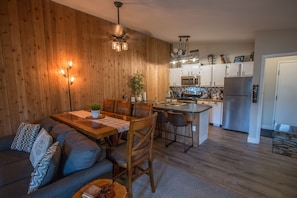 A modern kitchen with wooden walls, a dining area with a wooden table and chairs, and a built-in island with a sink. - Fully Remodeled, Two Bed, Two Bath, Best Views, Steps from Town  (Winter Park)