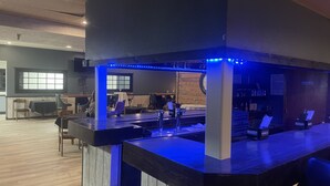 Zona de bar con mostrador, asientos y pared de madera.