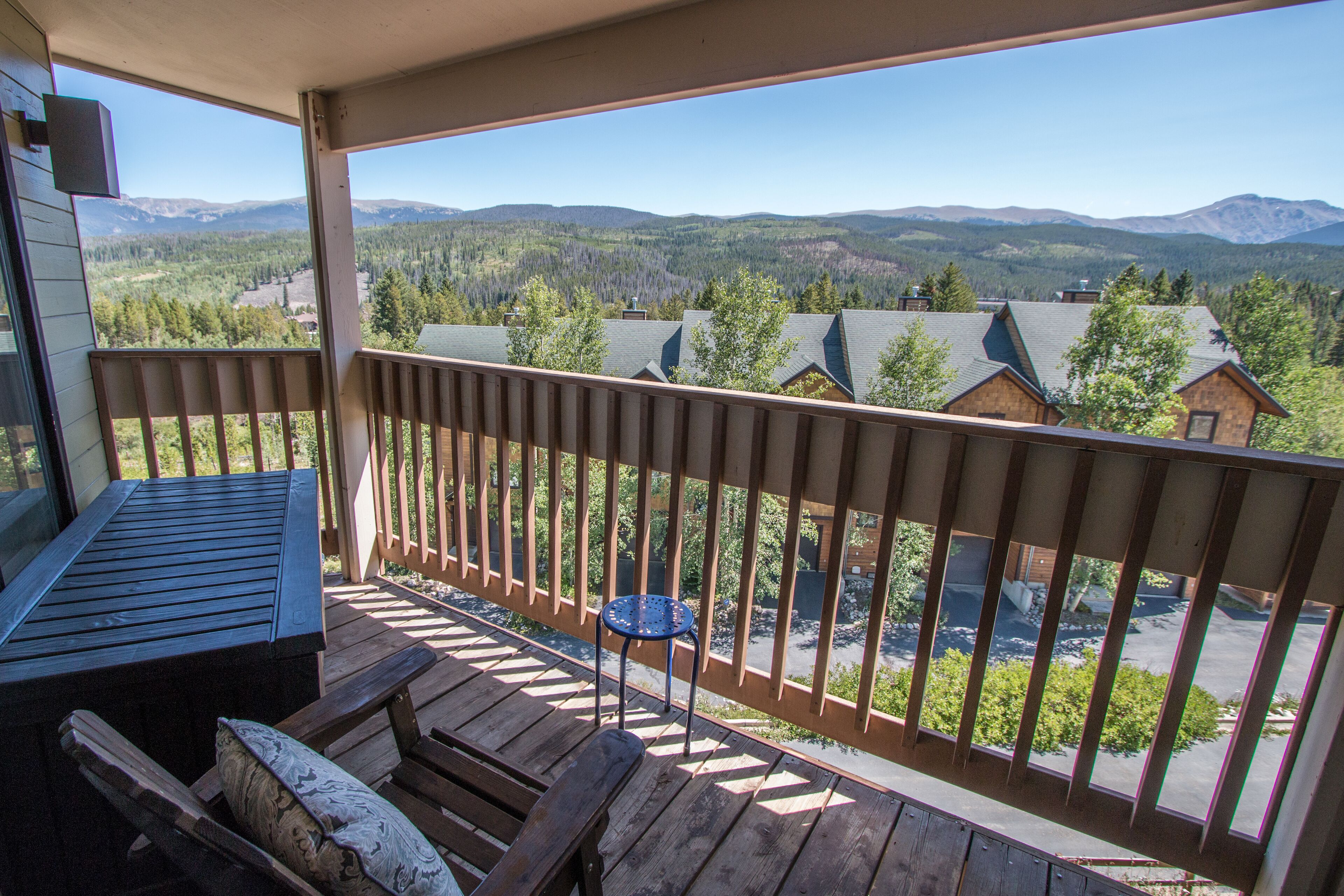 Eine Holzterrasse mit Tisch und Stühlen mit Blick auf eine gebirgige Landschaft mit Häusern.