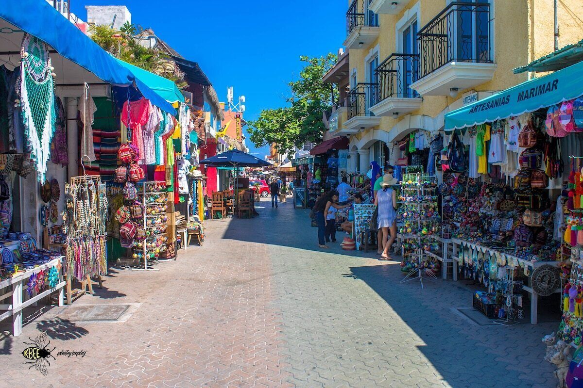 Ein belebter Markt mit verschiedenen Ständen, an denen bunte Textilien und Kunsthandwerk angeboten werden.