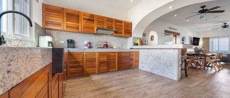 A modern kitchen with wooden cabinets, a granite countertop, and a central island.