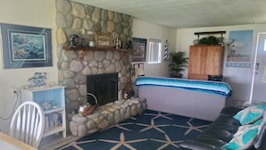 A living room with a stone fireplace, a sofa, a star-patterned rug, and a wooden cabinet.