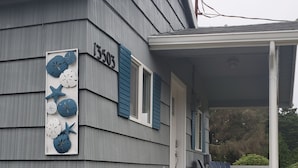 A house with a gray exterior, a porch with wooden steps, and a 'Welcome' sign.