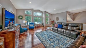 A spacious living room with a large TV, leather sofa, blue armchair, and a wooden coffee table. - Quiet Mtn 4BR, 3BA, Spa, Poker, Central AC (South Lake Tahoe)