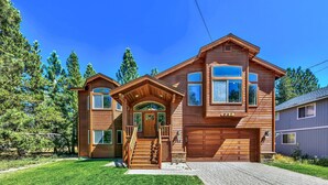 A two-story wooden house with a front porch, a garage, and a well-maintained lawn. - Quiet Mtn 4BR, 3BA, Spa, Poker, Central AC (South Lake Tahoe)
