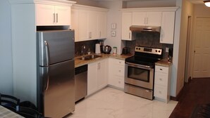 Una cocina moderna con electrodomésticos de acero inoxidable, armarios blancos y salpicadero de azulejos.