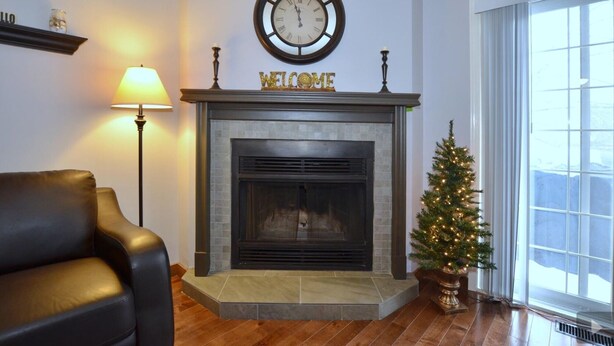 Una sala de estar con chimenea, un reloj, un árbol de Navidad y un sillón de cuero.