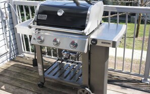 A portable Weber Genesis II grill with three burners, a side vent, and a digital thermometer.