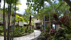 A tropical garden pathway leading to a building with a curved roof and a stone walkway. - Exotic Kona Bay Hawaii Beachfront Tropical Paradise Stunning Home. (Kailua-Kona)