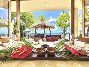 Mesa lista para comer con vista al océano y palmeras.