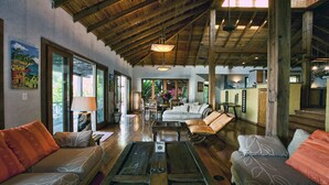 A spacious living room with a high ceiling, wooden beams, and large windows allowing natural light. - Mariposa Del Mar: Spectacular Ocean front Villa with private pool. (Roatan)