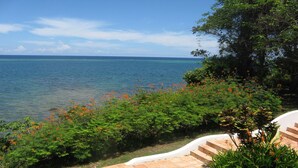 A coastal view with a clear sky, a calm sea, and a pathway leading to a staircase. - Mariposa Del Mar: Spectacular Ocean front Villa with private pool. (Roatan)