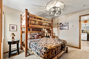 Un lit superposé avec une couvre-lit à motifs, une lampe de chevet et un tableau encadré au mur.