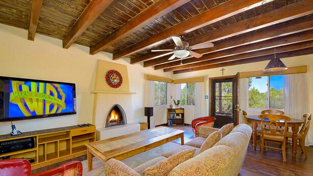 A living room with a fireplace, a television, and a ceiling fan. - Peaceful Hilltop Casita w/ Stunning Views, Close to the Historic Plaza (Santa Fe)