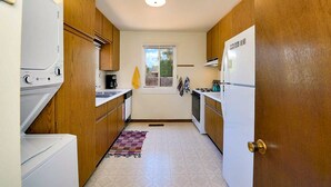 A compact kitchen with wooden cabinets, a washing machine, a stove, and a refrigerator. - Peaceful Hilltop Casita w/ Stunning Views, Close to the Historic Plaza (Santa Fe)
