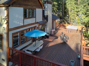 Una terraza de madera con mobiliario exterior, que incluye una mesa y sillas, y una zona cubierta para la parrilla.