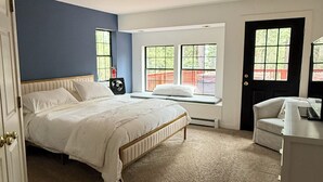 Un dormitorio con una cama, un escritorio y dos ventanas.