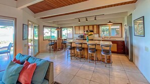 Una cocina amplia con barra, techo de madera y ventanas grandes.