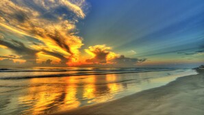 Una playa con un atardecer, agua tranquila y cielo despejado.