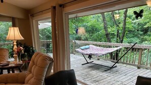 Ein Zimmer mit einem großen Fenster, einer Hängematte und Blick ins Freie.