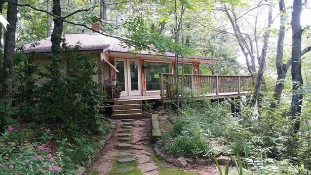 Eine rustikale Holzhütte mit einer Holzterrasse und einem Kiesweg, der zum Eingang führt.