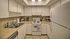 A compact kitchen with white cabinets, a stove, a sink, and a refrigerator. - Short/Long Stays; Sun, Fun, & Relax in the Gardens.  (Palm Beach garden)
