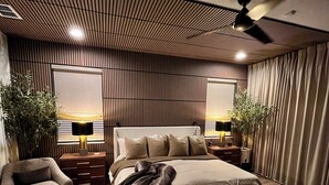 Une chambre moderne avec un grand lit, un ventilateur de plafond et une vue sur le coucher de soleil par les fenêtres.