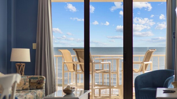 Une pièce avec vue sur l’océan, comprenant un canapé, un fauteuil, une table et une lampe.