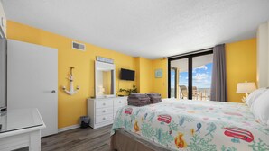 Une chambre d’hôtel avec un lit, un bureau, une commode, un miroir, une télévision et une vue sur le ciel.