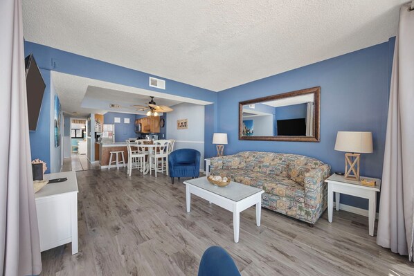 A living room with a sofa, coffee table, and a dining area with chairs and a table.