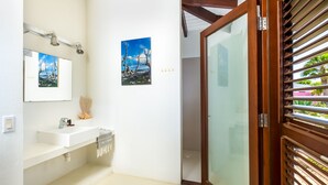 Un baño con un lavamanos blanco, un espejo y dos cuadros en la pared.