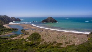 A coastal landscape with a beach, rocky outcrops, and a clear blue sky. - Oceanfront Vacation Home - Spectacular Views; Hot Tub; Wi-Fi. (Elk)