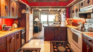 A kitchen with wooden cabinets, a central island, and a view to the outside. - Oceanfront Vacation Home - Spectacular Views; Hot Tub; Wi-Fi. (Elk)