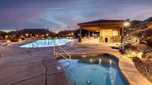 A swimming pool area with two pools, a covered seating area, and a building with a caution sign. - Desert Paradise Getaway-Pool is Open! (Washington)