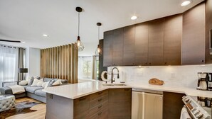 A modern kitchen with dark wooden cabinets, a white countertop, and stainless steel appliances. - Canyons Hidden Creek Studio on the Duck  Pond (Park City)
