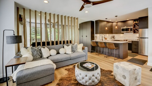 A modern living room with a grey sofa, a round ottoman, and a coffee table. - Canyons Hidden Creek Studio on the Duck  Pond (Park City)
