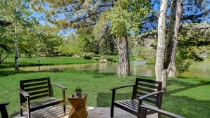 A park with two wooden benches facing a pond, surrounded by trees and grass. - Canyons Hidden Creek Studio on the Duck  Pond (Park City)