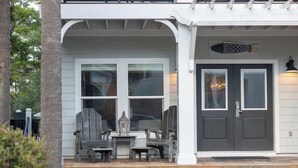 A building with a porch, two doors, and a small table with chairs. - Seacrest Luxury Beach House - Sleeps 14 (Seacrest Beach)