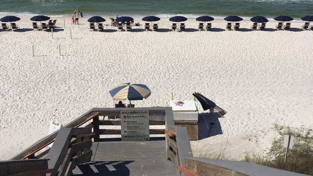 A beach with a wooden boardwalk leading to the shore, beach chairs, and umbrellas. - Seacrest Luxury Beach House - Sleeps 14 (Seacrest Beach)