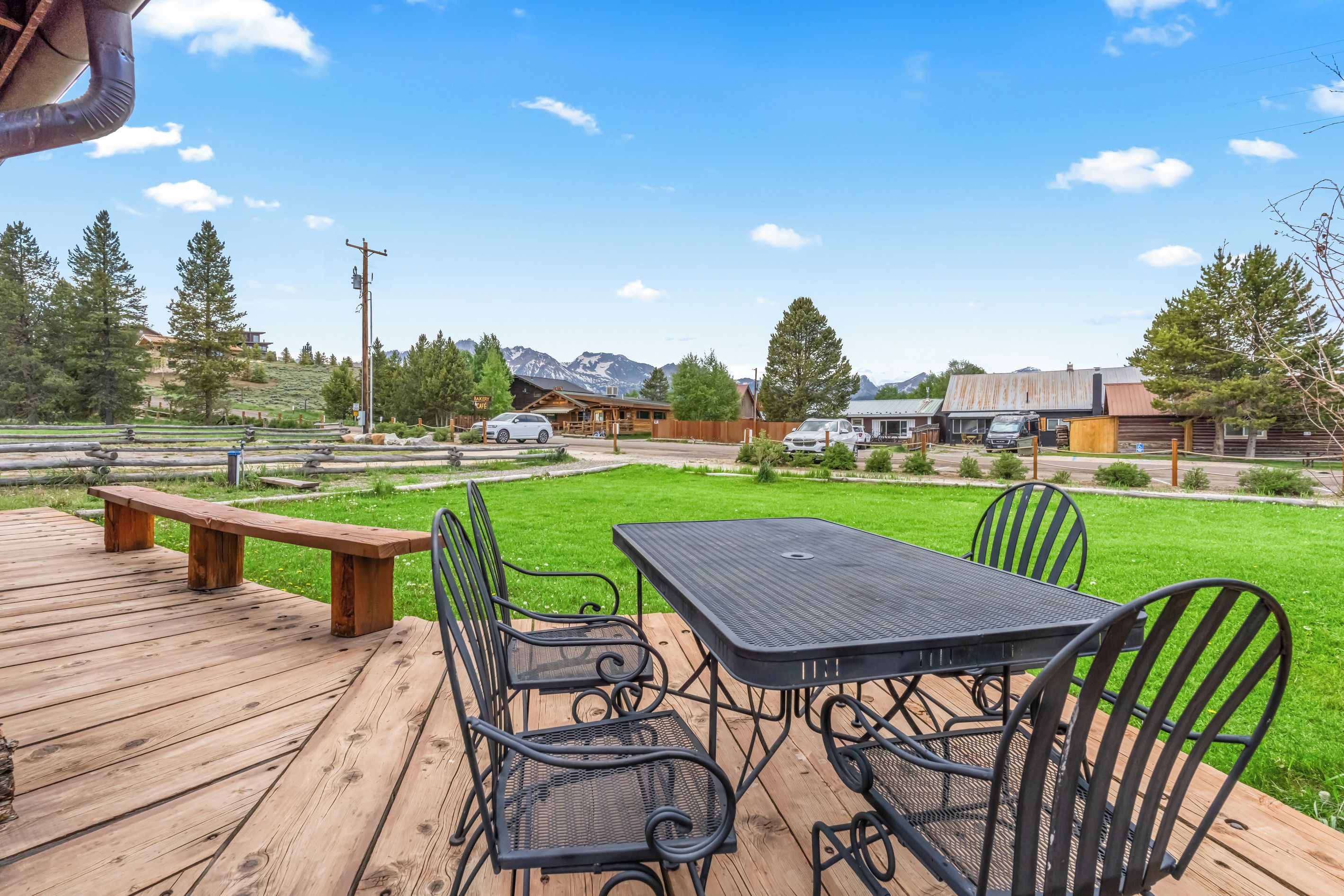A deck with a table and chairs, a picnic table, and a view of a mountain range.