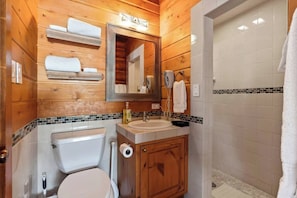 Een badkamer met houten lambrisering, een toilet, een wastafel en een spiegel.