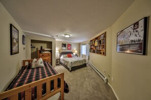 A bedroom with a bed, bedside tables, a dresser, a bookshelf, and a poster on the wall.
